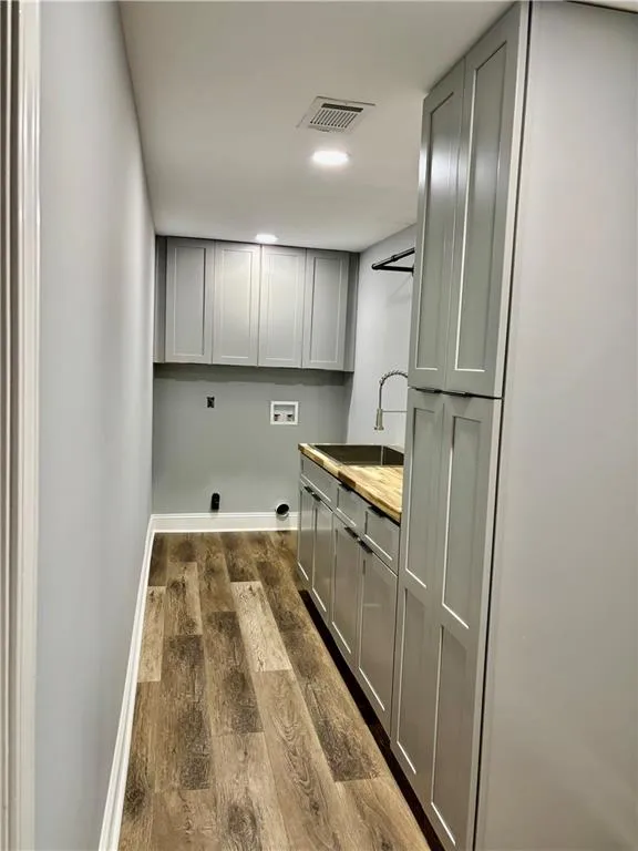 Laundry room with cabinet space, washer hookup, dark wood-style floors, hookup for an electric dryer, and baseboards