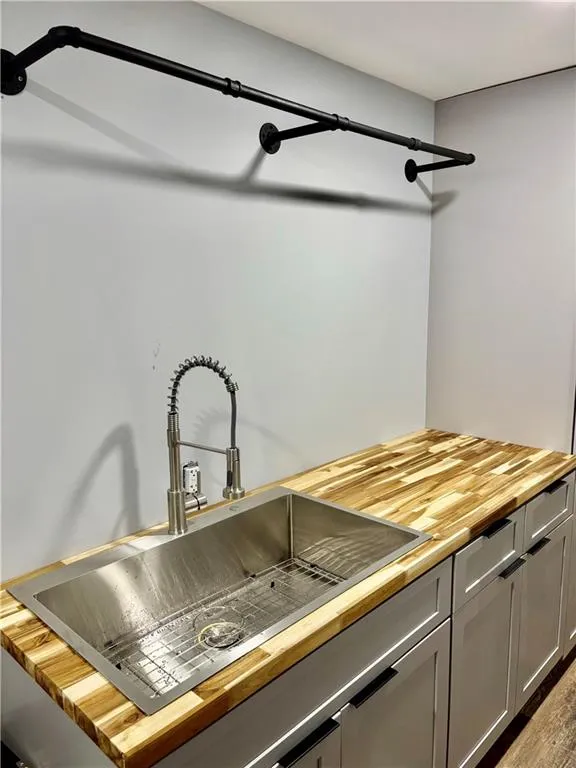 Kitchen view of butcher block countertops, a sink, and gray cabinetry