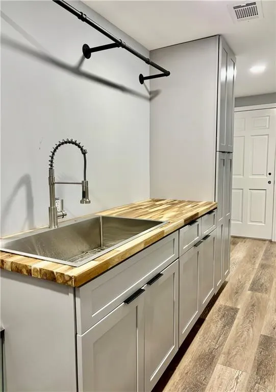 Kitchen featuring butcher block countertops, a sink, and light wood-type flooring