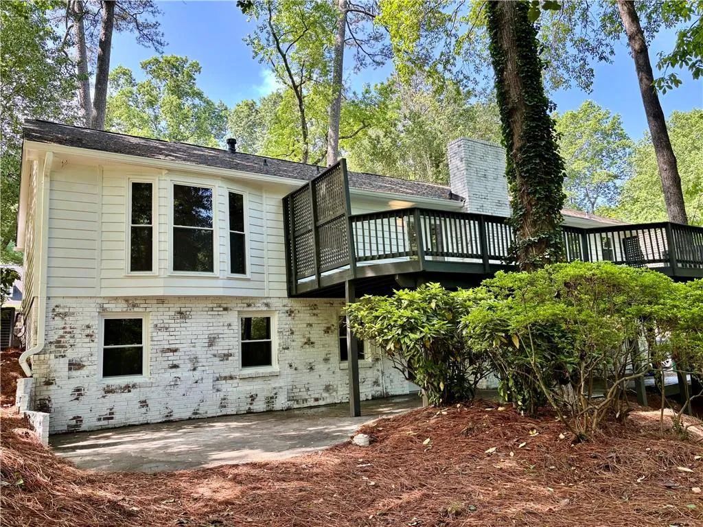 Rear view of property with a wooden deck, brick siding, a patio area, and central AC unit