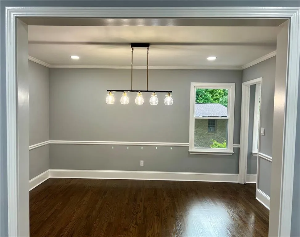 Unfurnished dining area with dark wood-style flooring, crown molding, baseboards, and recessed lighting