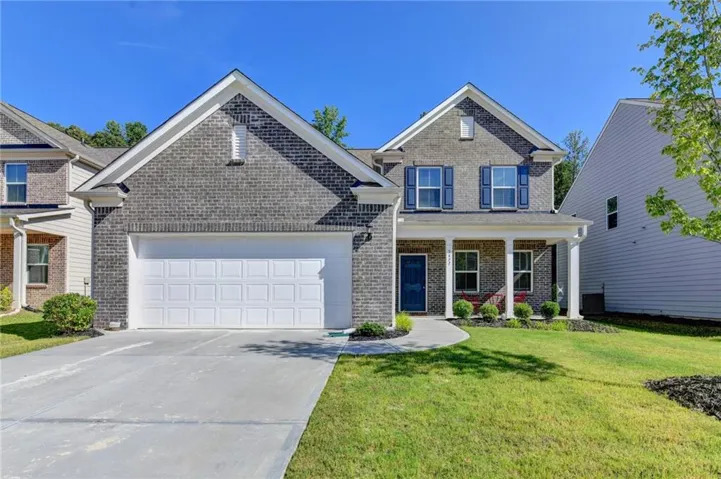 Brick facade residence with a two-car garage, covered entry porch, and a blue front door