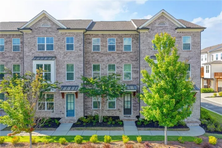 Multi-story brick townhouse featuring a gabled roofline, multiple windows, and a prominent bay window