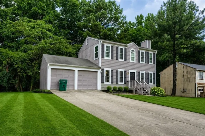 Two-story residence featuring light gray siding, dark shutters, and a front entry porch with steps
