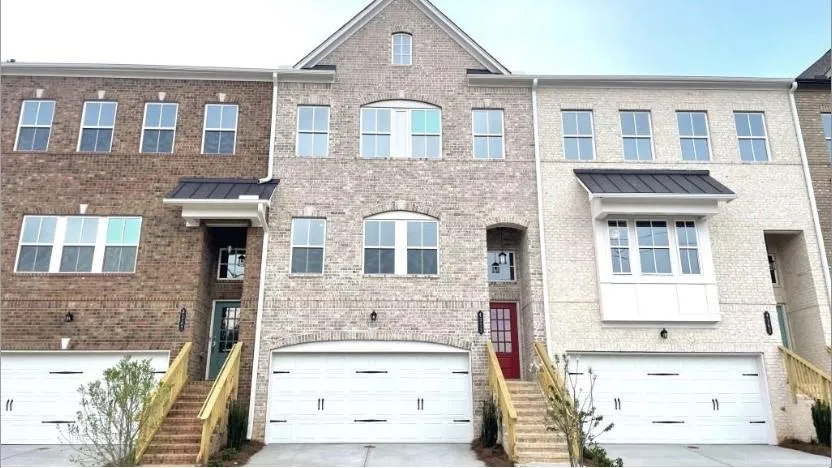 Contemporary townhome facade featuring a two-car garage, brick exterior, and a red entry door