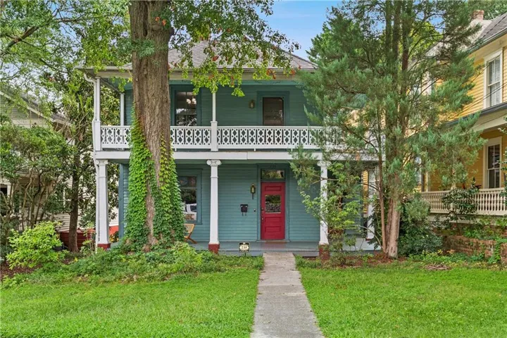 Two-story exterior with a covered porch and upper balcony featuring decorative white railings and columns