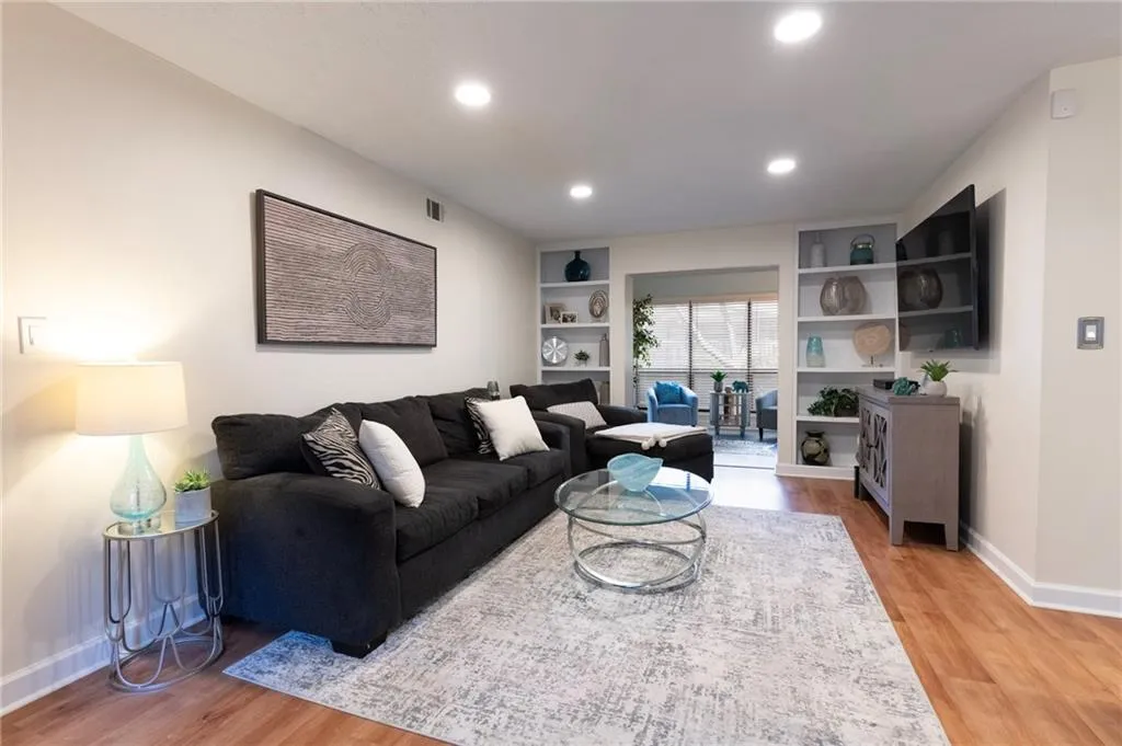 Living area with light wood finished floors, built in shelves, and recessed dimmable lighting