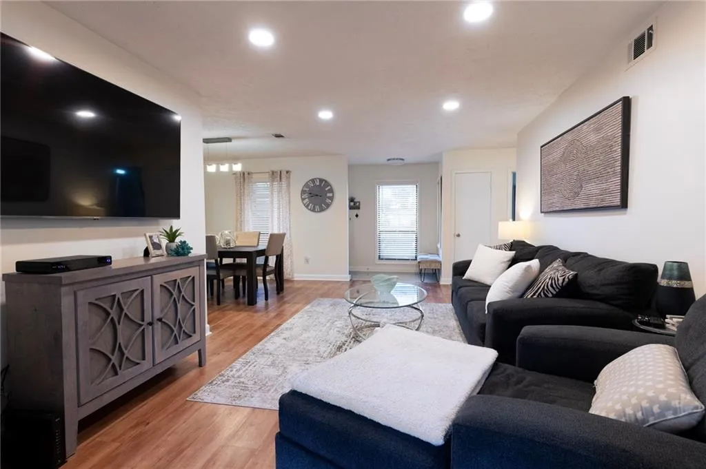 Living area with light wood finished floors, built in shelves, and recessed dimmable lighting