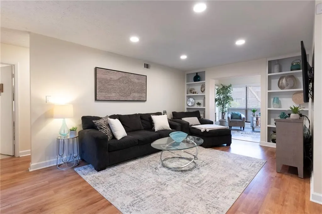 Living area with light wood finished floors, built in shelves, and recessed dimmable lighting