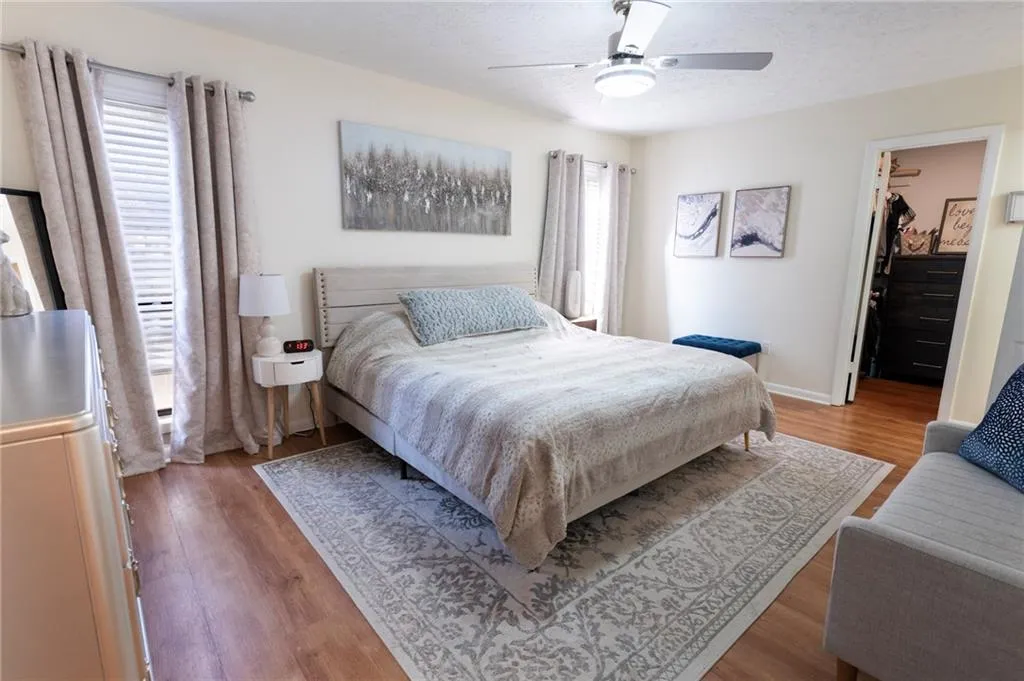 Bedroom featuring a spacious walk-in closet, light wood finished floors, a ceiling fan, and a textured ceiling