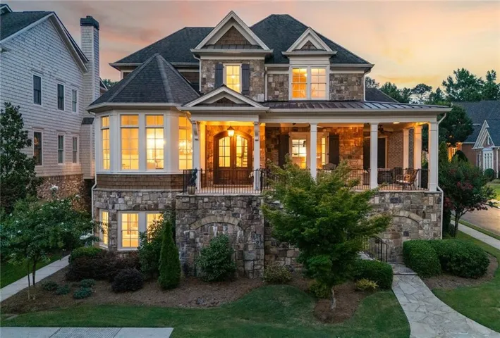 Stone and shake exterior with a covered front porch, prominent bay window, double entry doors, and a stone walkway