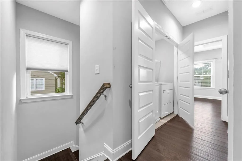 Hall with an upstairs landing, dark wood finished floors, and washer / dryer