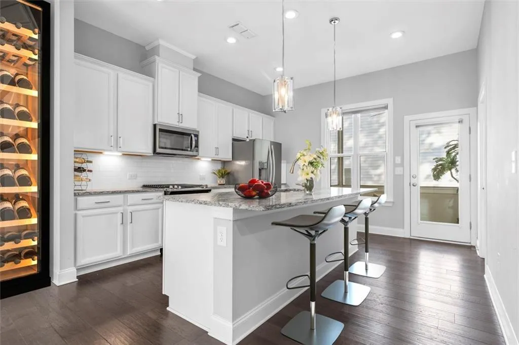 Kitchen with light stone countertops, tasteful backsplash, a kitchen bar, an island with sink, and recessed lighting