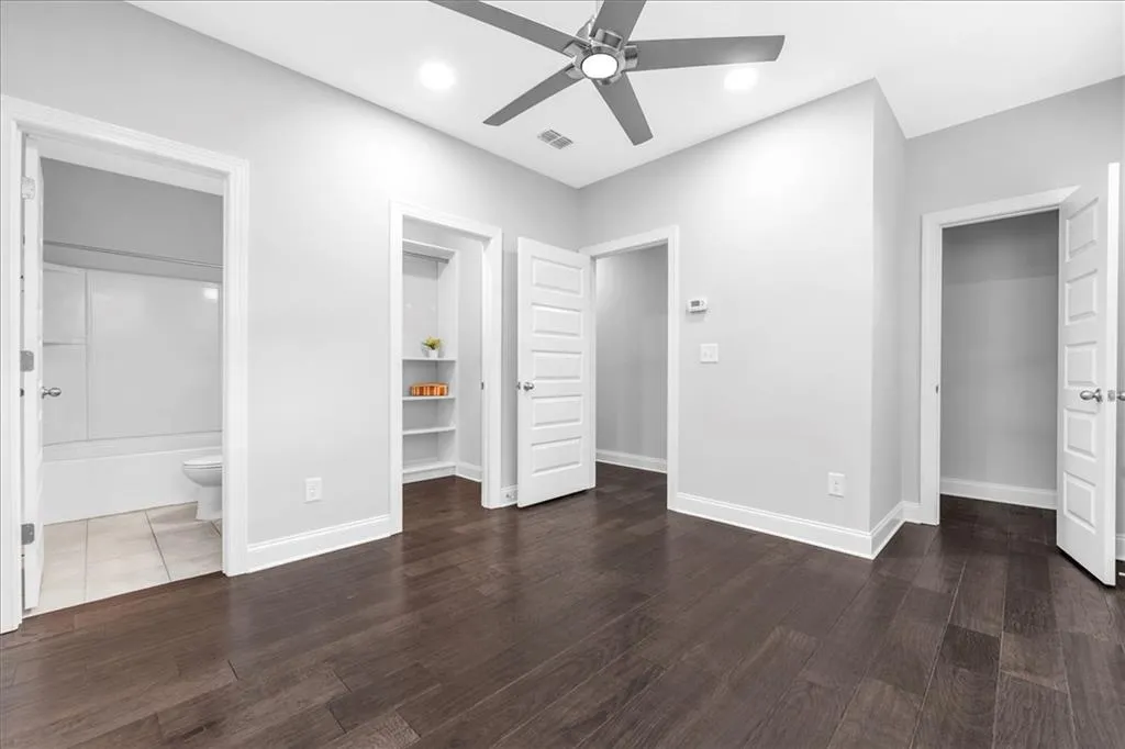 Unfurnished bedroom with connected bathroom, ceiling fan, dark wood finished floors, and recessed lighting