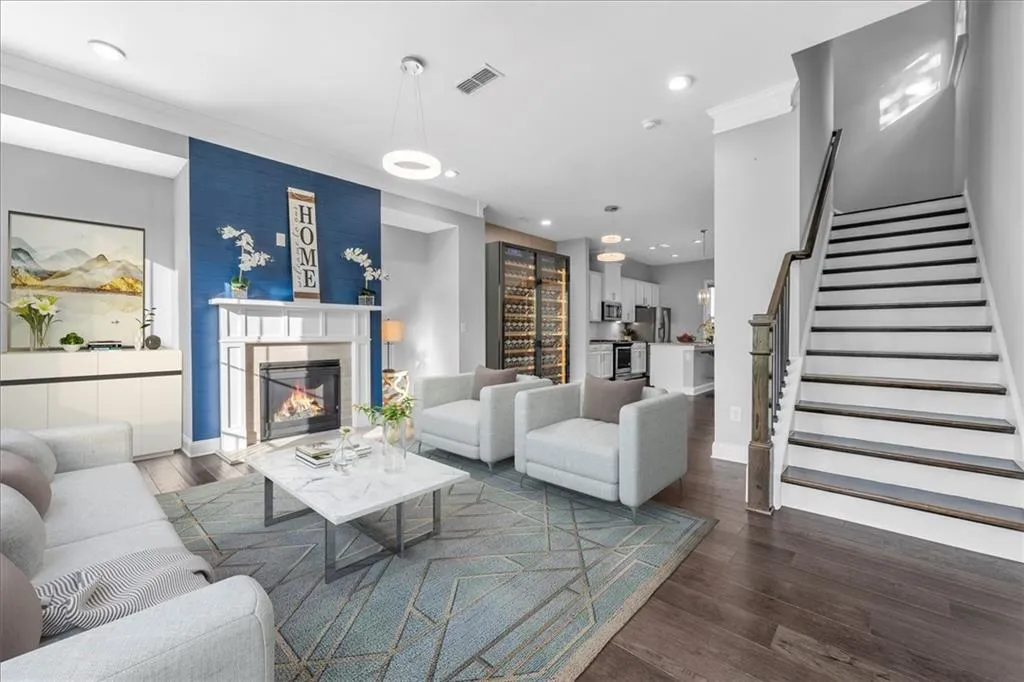 Living room with stairway, dark wood-style floors, a glass covered fireplace, and recessed lighting