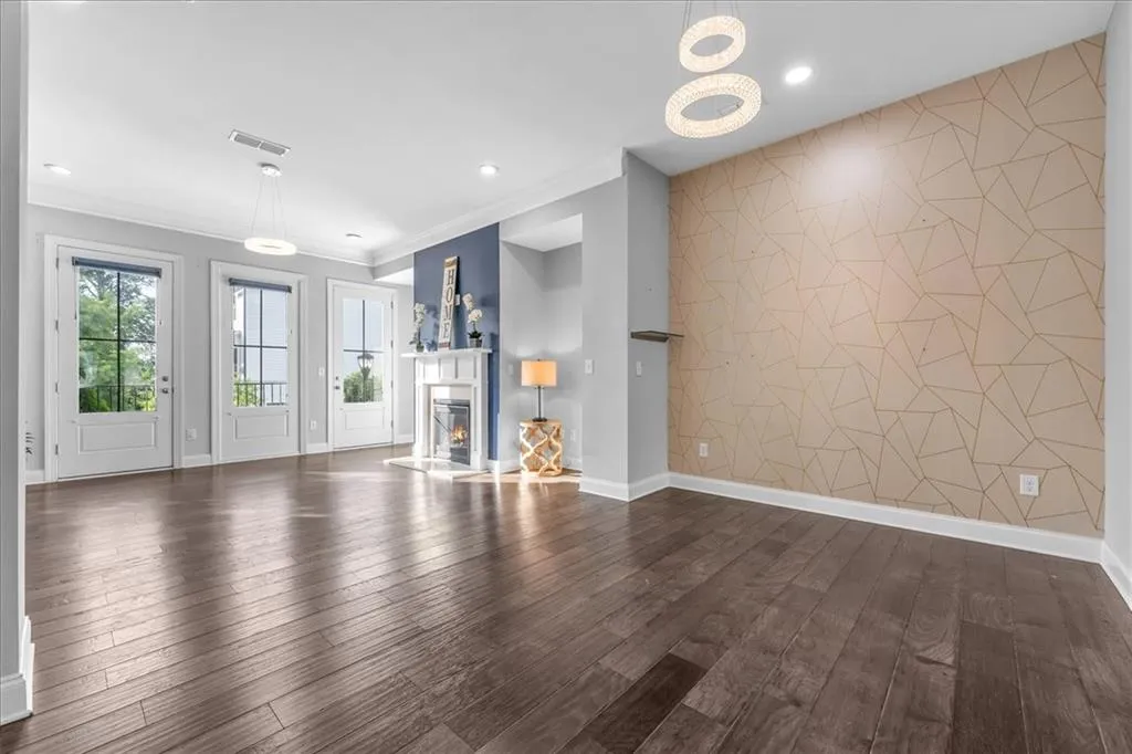 Unfurnished living room with an accent wall, a glass covered fireplace, dark wood-style flooring, ornamental molding, and recessed lighting
