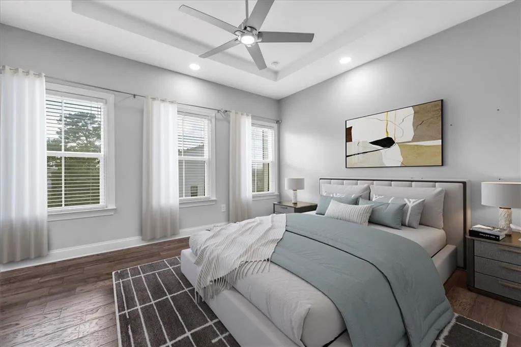 Bedroom featuring a raised ceiling, hardwood / wood-style flooring, multiple windows, recessed lighting, and a ceiling fan