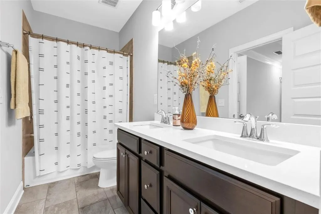 Bathroom with shower / bath combination with curtain, double vanity, and light tile patterned flooring