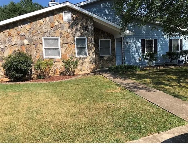 Stone veneer and painted siding exterior with a concrete walkway and landscaped beds