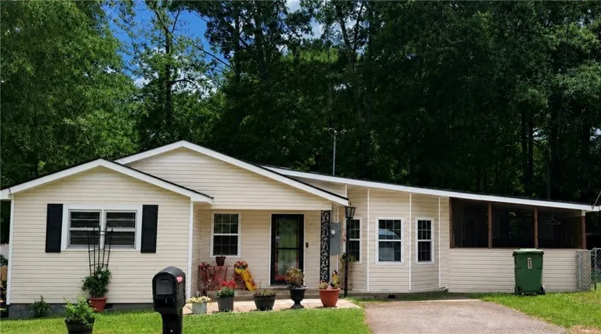 Cream-colored siding residence featuring a screened-in porch, black framed windows, and a paved driveway