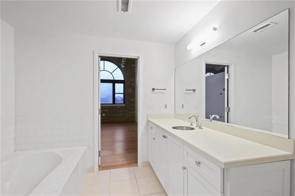Bathroom featuring a spacious vanity with white cabinetry, a single undermount sink, and a large mirror