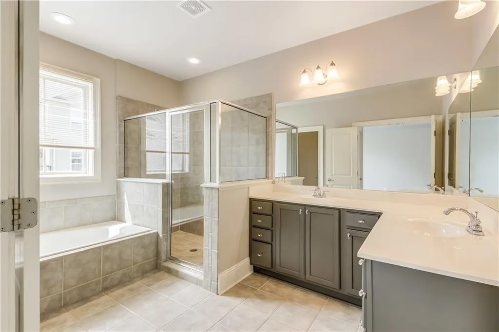 Bathroom featuring double vanity, light tile patterned floors, a bath, a shower stall, and recessed lighting