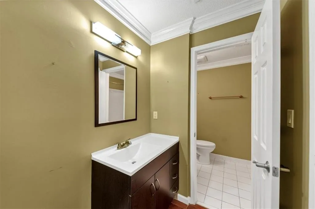 Bathroom with tile patterned flooring, crown molding, and vanity