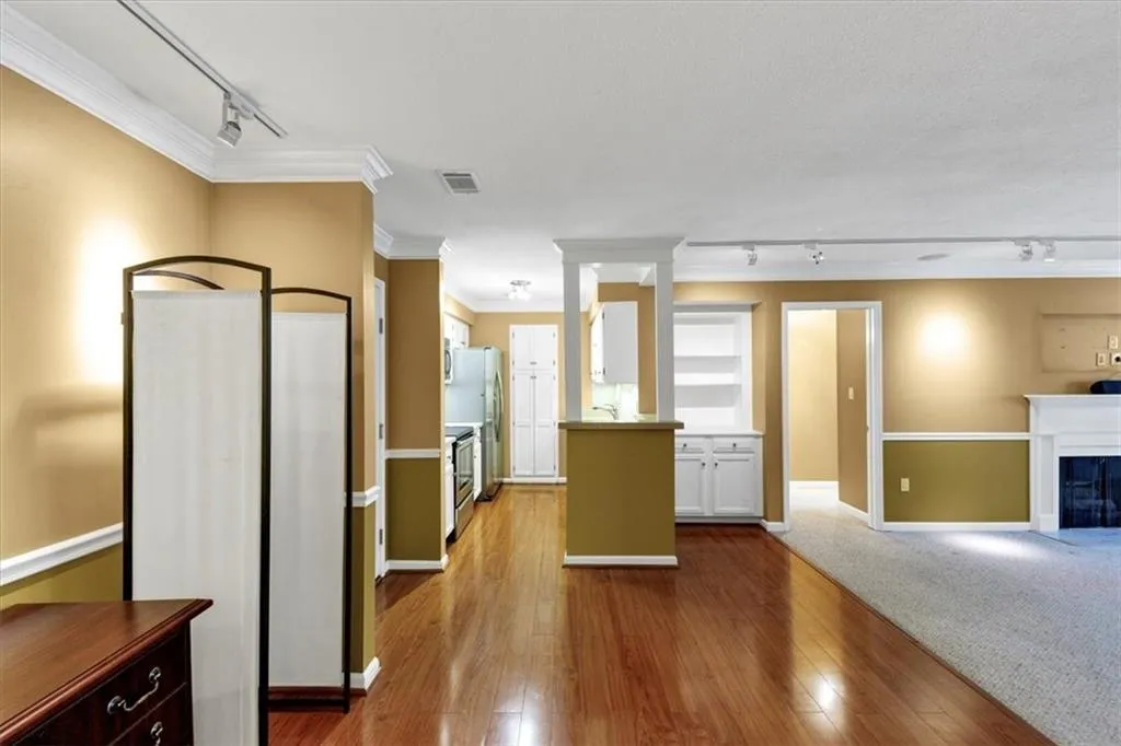 Kitchen with rail lighting, ornamental molding, hardwood / wood-style flooring, a fireplace, and light countertops