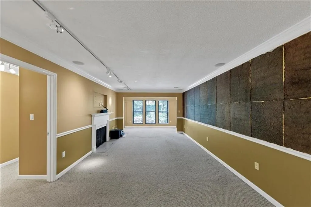 Unfurnished living room with track lighting, carpet flooring, a fireplace, ornamental molding, and a textured ceiling
