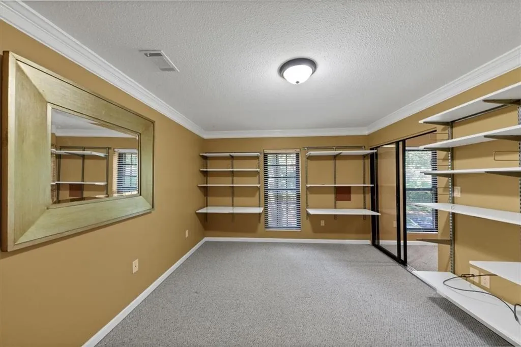 Unfurnished room with a textured ceiling, light carpet, and crown molding