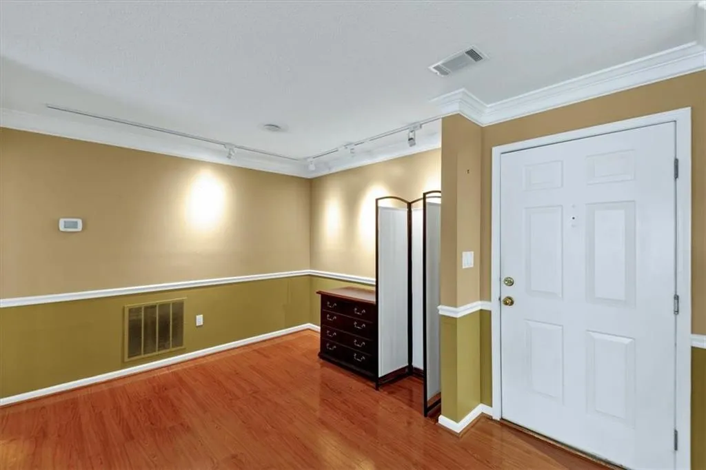 Foyer entrance with rail lighting, wood finished floors, and crown molding
