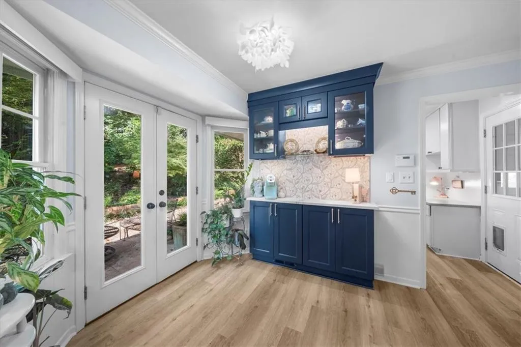 Bar with blue cabinets, glass insert cabinets, french doors, decorative backsplash, and crown molding