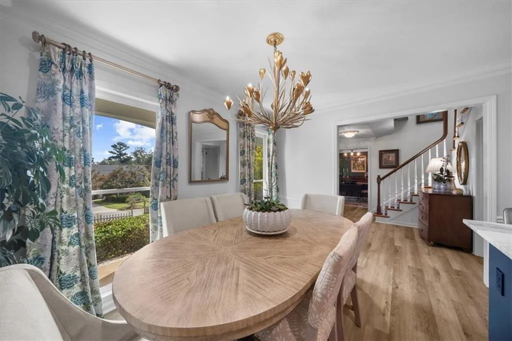 Dining area with crown molding, light wood-style flooring, a chandelier, and stairs