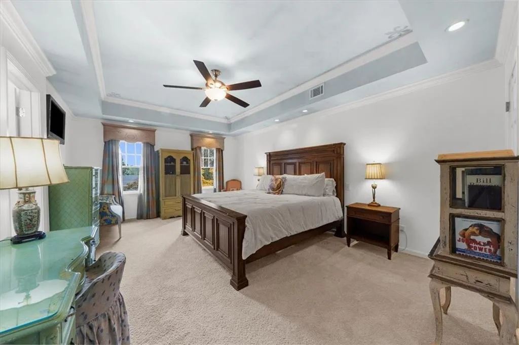 Bedroom featuring a tray ceiling, crown molding, light carpet, a ceiling fan, and recessed lighting