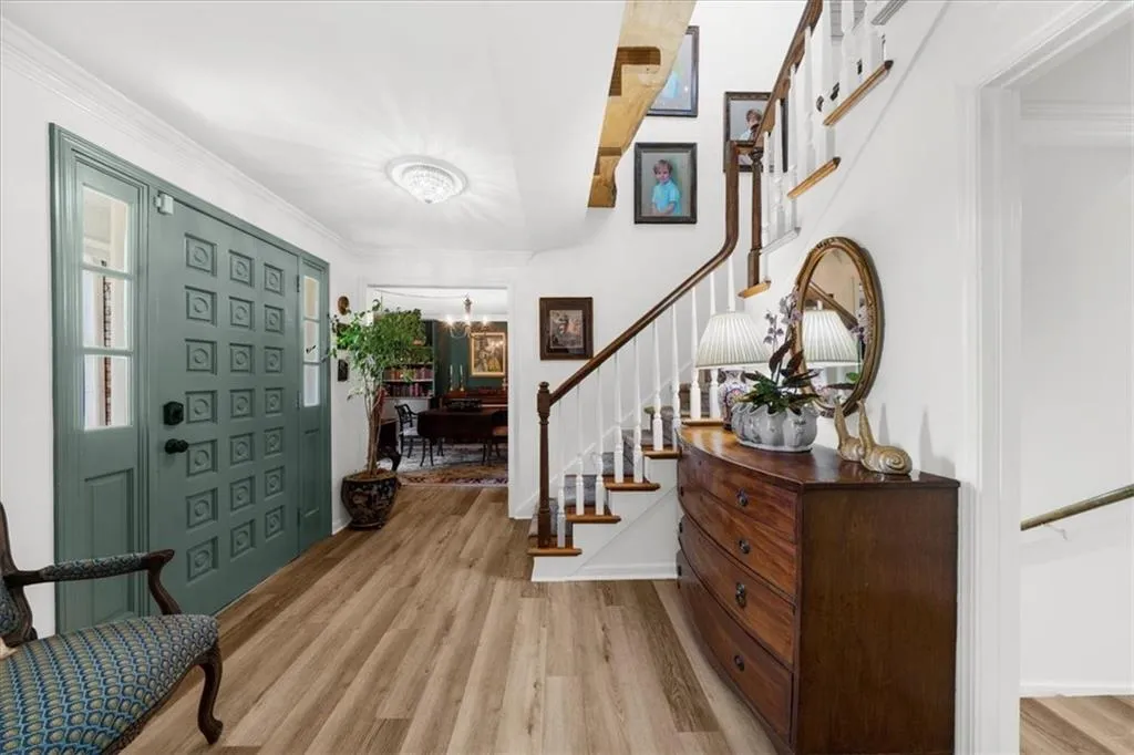 Foyer featuring stairs, light wood-style floors, crown molding, and a chandelier