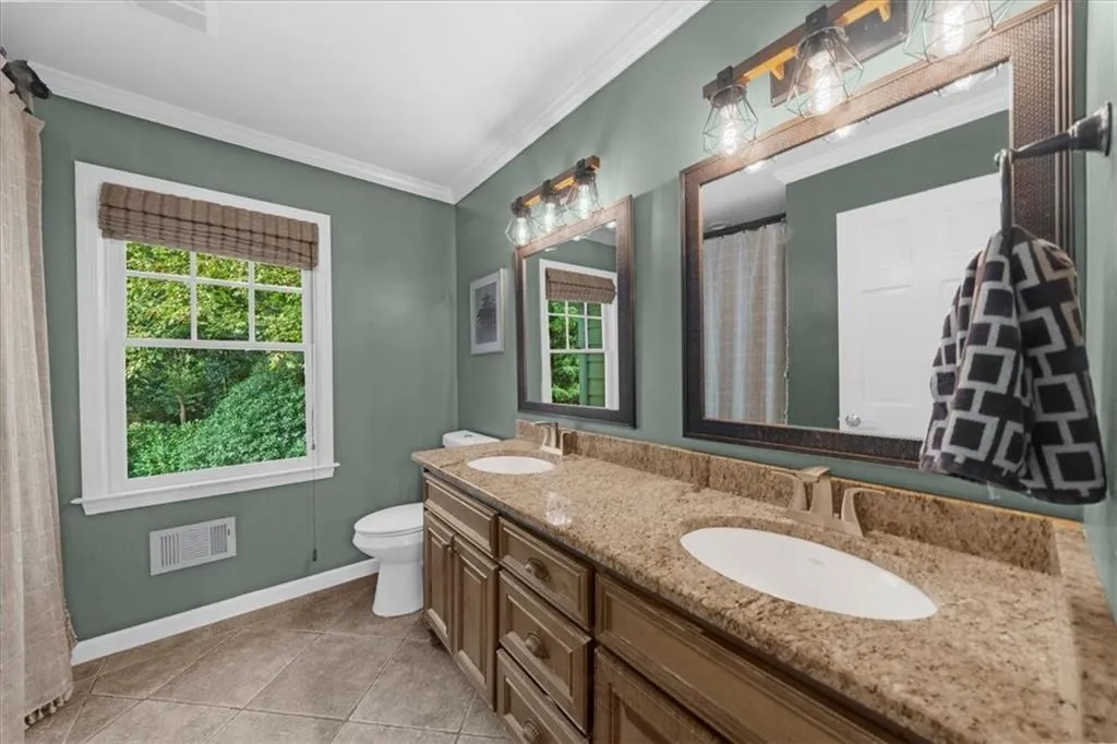 Bathroom featuring double vanity, curtained shower, light tile patterned flooring, and ornamental molding