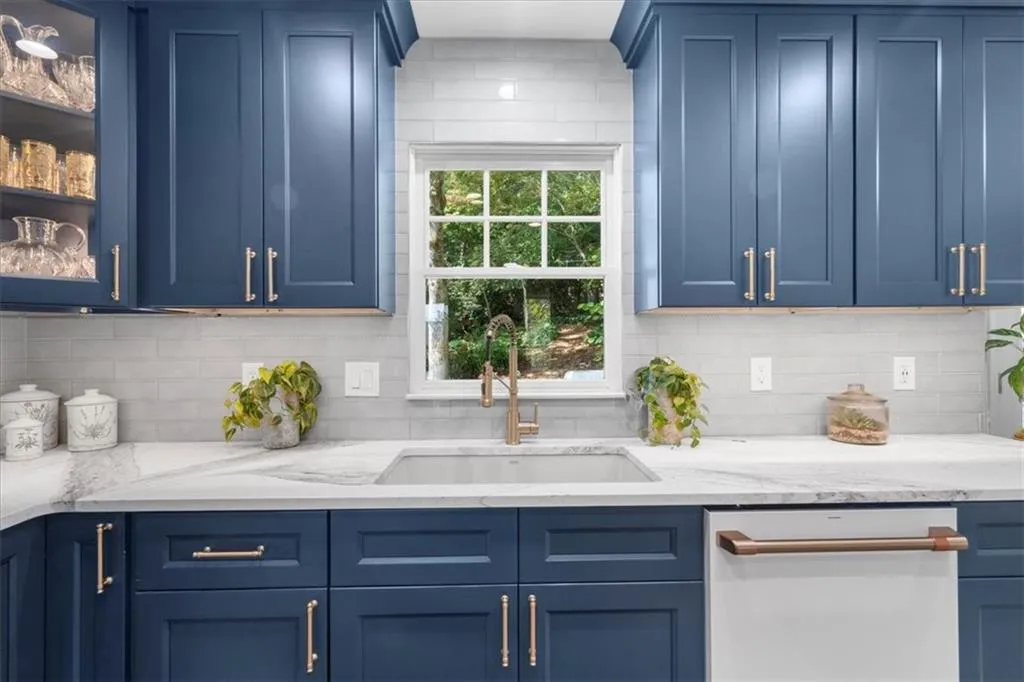 Kitchen featuring blue cabinetry, light stone counters, and decorative backsplash