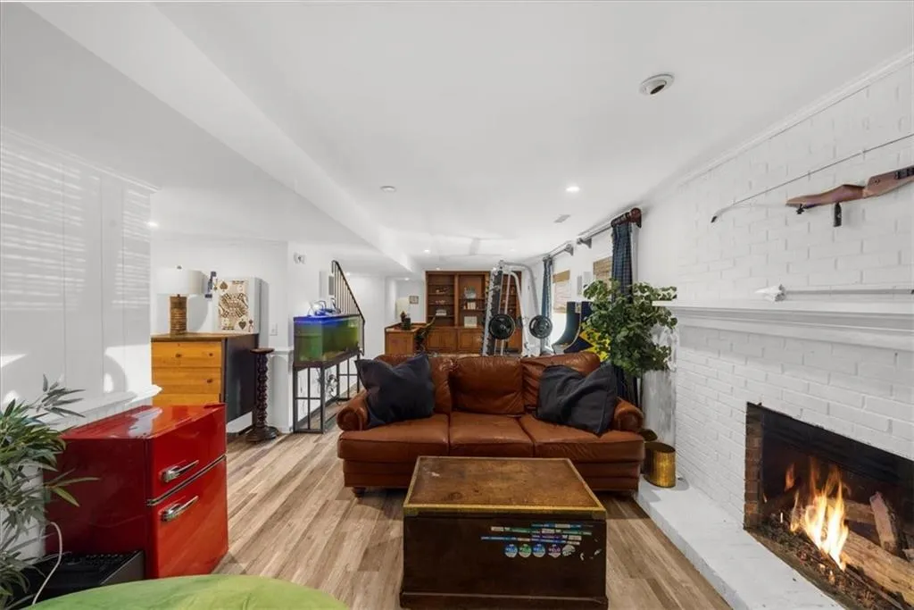 Living room featuring light wood-style flooring, a fireplace, and brick wall