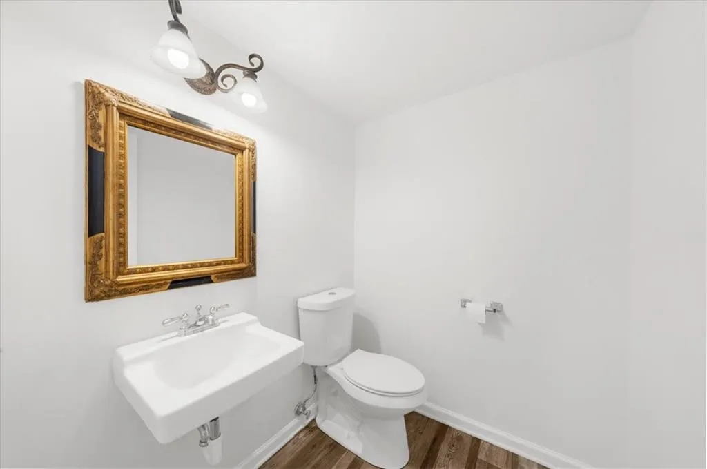 Half bathroom with dark wood-style floors and baseboards