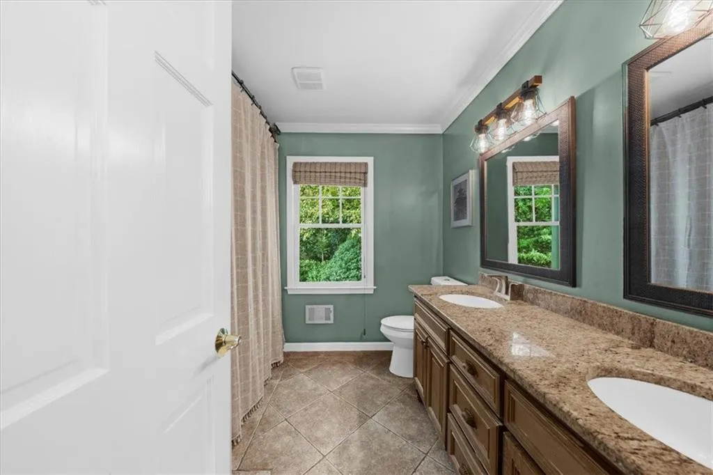 Bathroom featuring double vanity, curtained shower, ornamental molding, and light tile patterned flooring