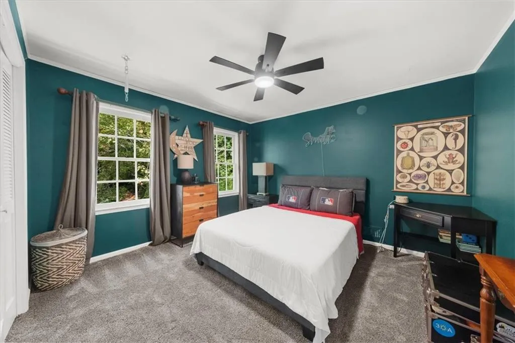 Carpeted bedroom with ornamental molding and ceiling fan