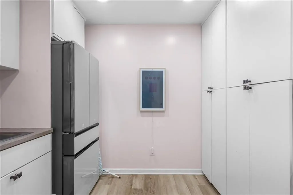 Kitchen with white cabinets, freestanding refrigerator, and light wood-style floors