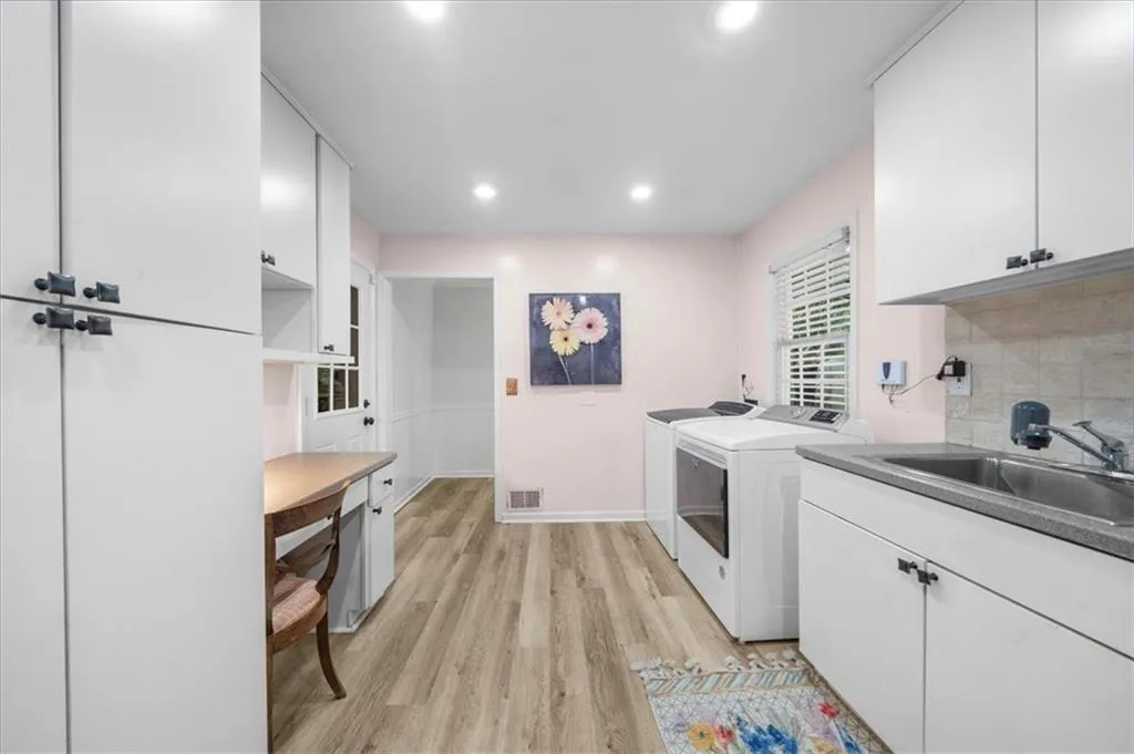 Washroom featuring cabinet space, light wood-style floors, recessed lighting, and separate washer and dryer