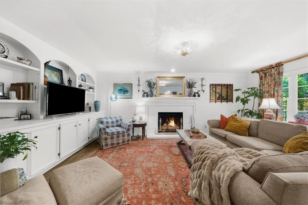 Living room featuring a lit fireplace and built in features