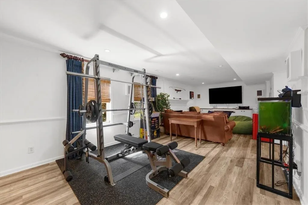 Exercise area with light wood-type flooring, recessed lighting, and crown molding
