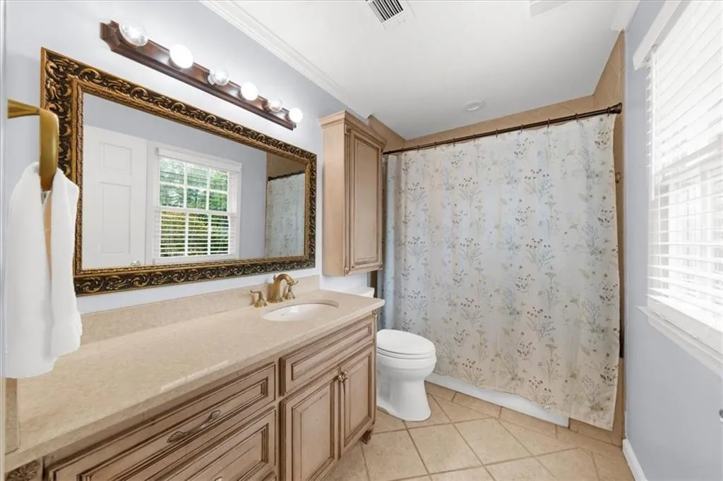 Bathroom with curtained shower, light tile patterned flooring, vanity, and ornamental molding