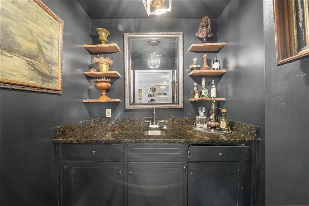 Indoor wet bar featuring open shelves and dark stone countertops