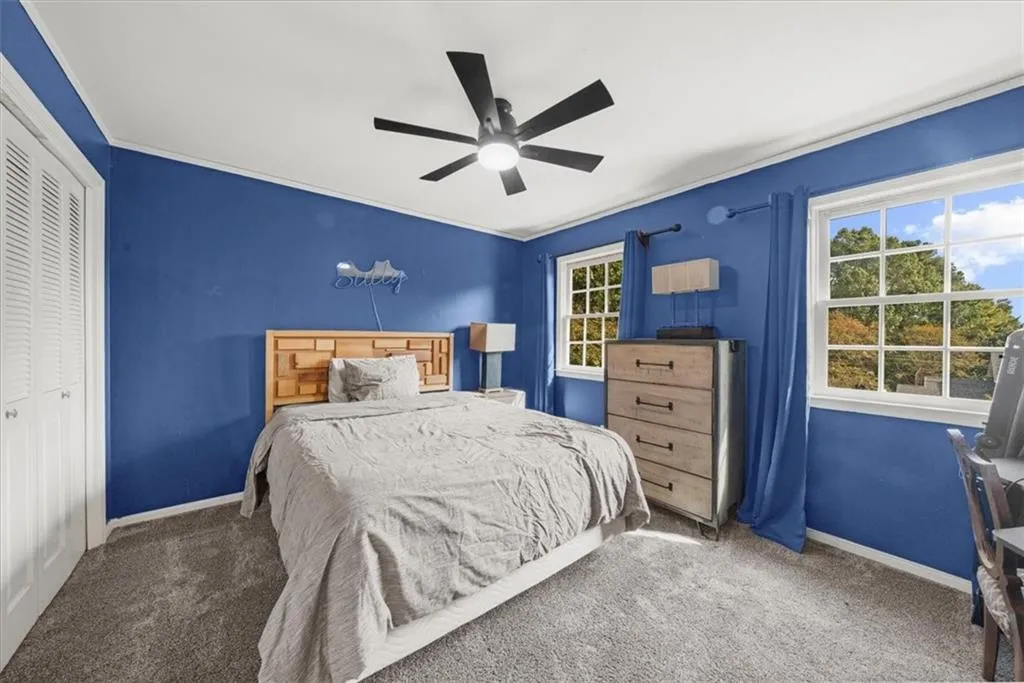 Bedroom with carpet, a closet, ornamental molding, and ceiling fan