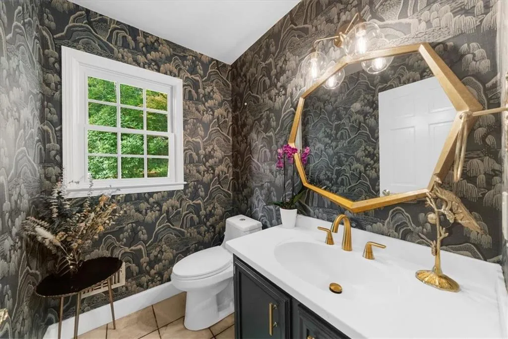 Bathroom with wallpapered walls, light tile patterned floors, and vanity