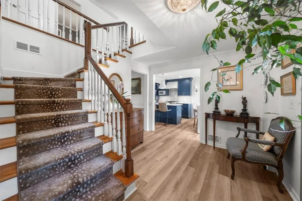 Stairs with wood finished floors and crown molding